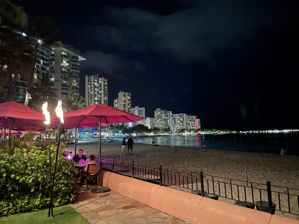 7 Best Luxury Hotels on Oahu (2025) Hawaii Calling a beach with a couple of people sitting at tables and umbrellas