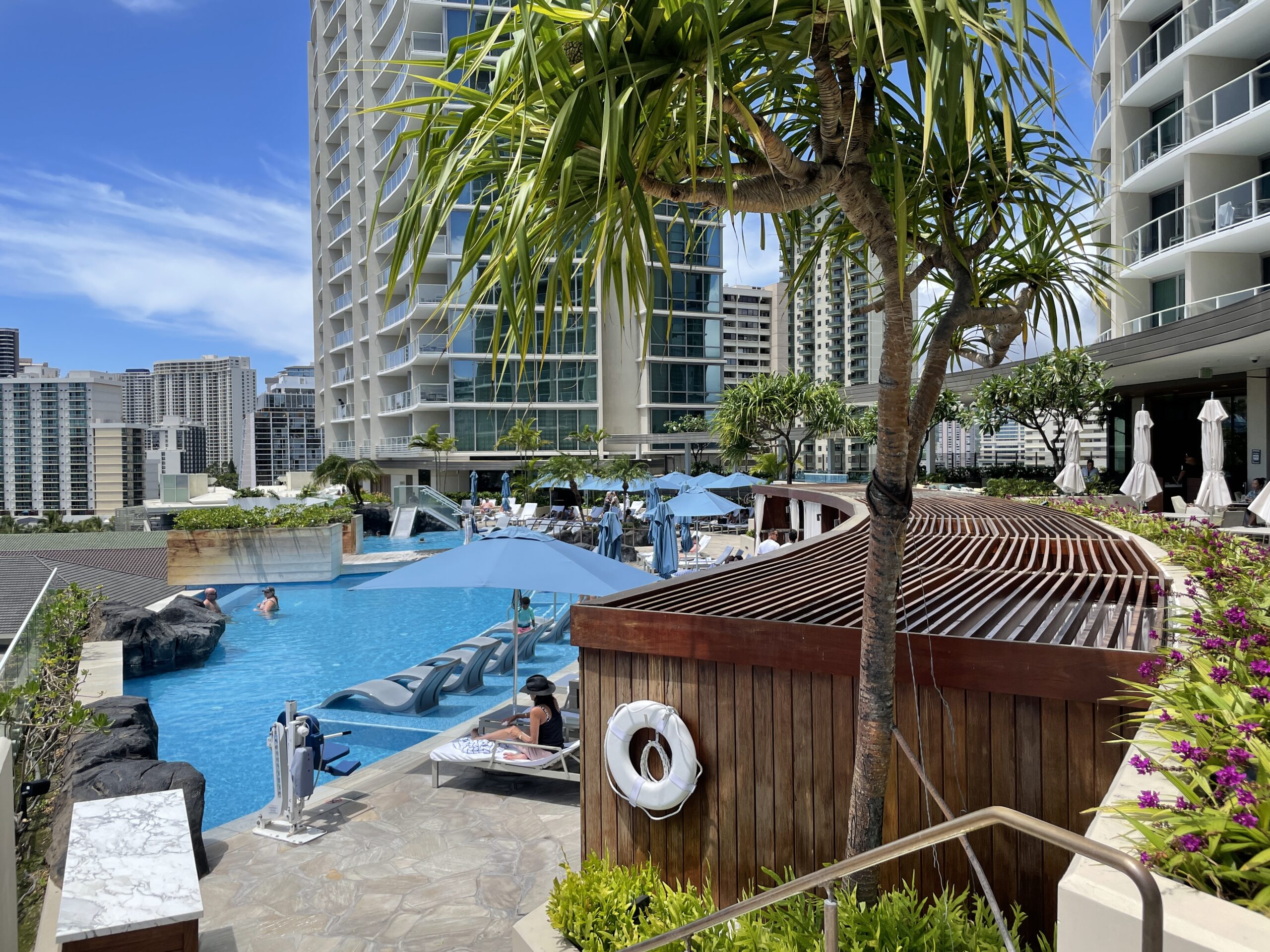 Review & Video: The Ritz-Carlton Waikiki Beach, Luxurious Residences & Hotel Hawaii Calling a pool with a palm tree and a building in the background