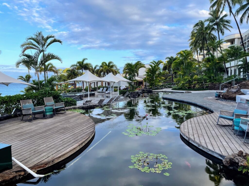 Review & Video: The Westin Hapuna Beach Resort Hawaii Calling a pool with a deck and chairs and a pond with trees and a blue sky