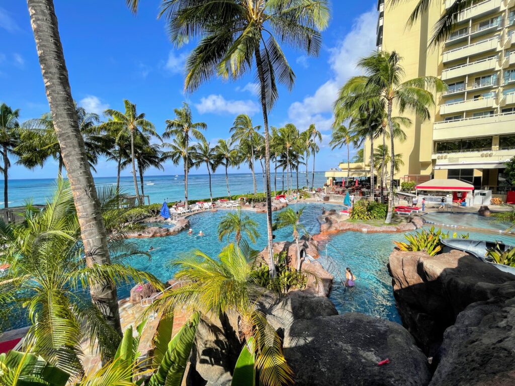 Review & Video: Sheraton Waikiki, Best Family Hotel on Oahu Hawaii Calling a pool with palm trees and a building in the background