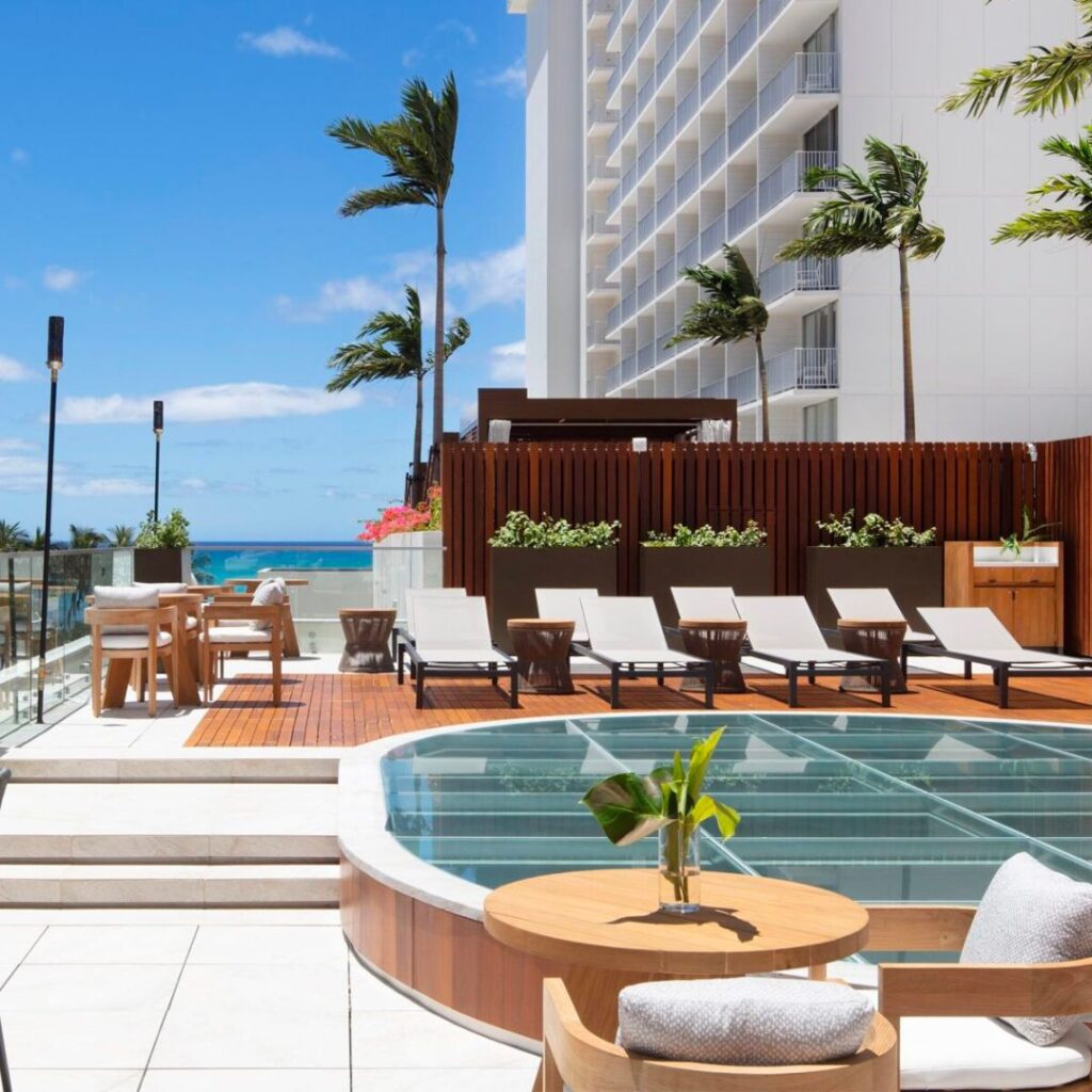 6 Amazing Boutique Hotels on Oahu (2025) Hawaii Calling a pool with chairs and a table in front of a building