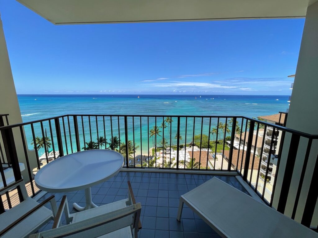 a balcony with chairs and a table overlooking the ocean