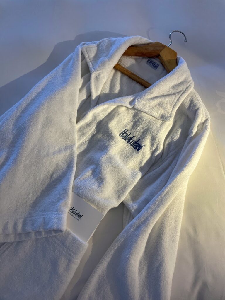 12 Plush & Cozy Hotel Robes Of The World Hawaii Calling One of the Halekulani hotel robes laying on a bed