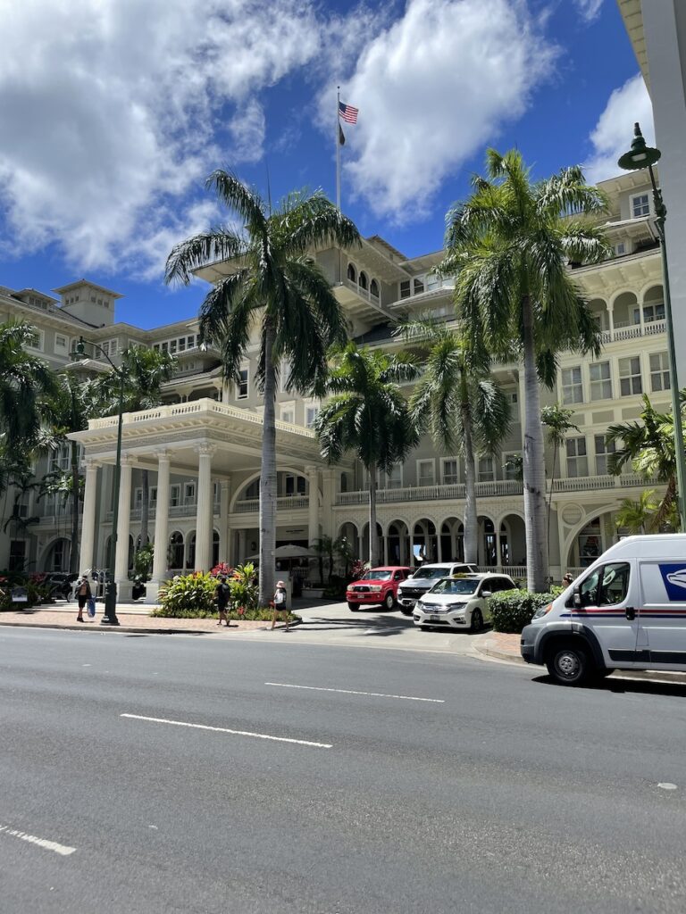 Review & Video: Moana Surfrider, Waikiki Beach Beauty Hawaii Calling a building with palm trees and cars parked on the side of the road