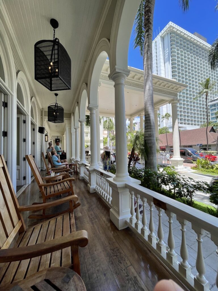 Review & Video: Moana Surfrider, Waikiki Beach Beauty Hawaii Calling a porch with chairs and a building in the background