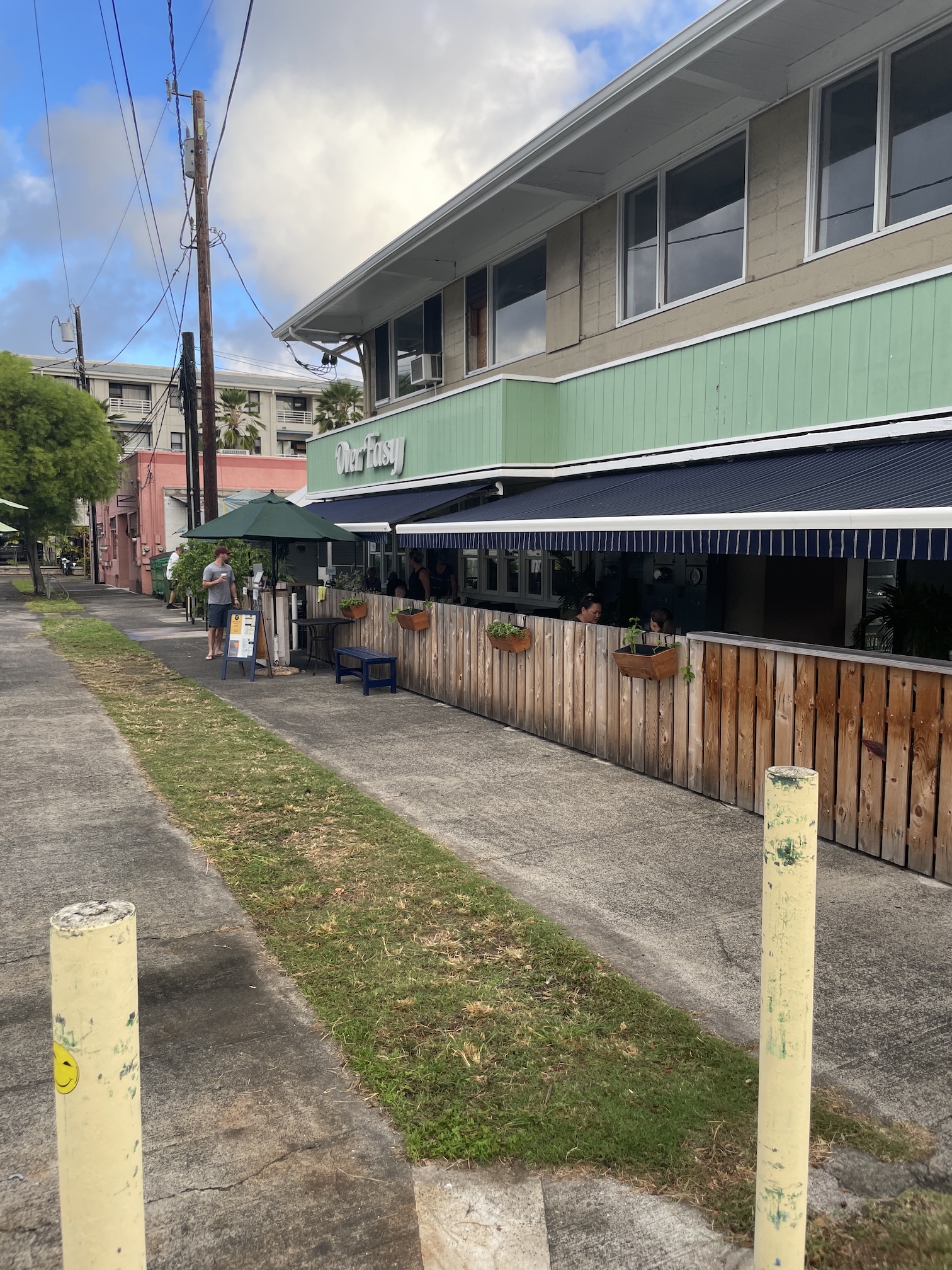 Over Easy Kailua | Breakfast Review Hawaii Calling a building with a wooden fence and people standing outside