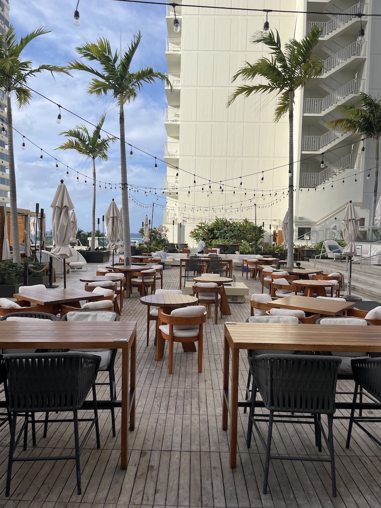 Review & Video: 'Alohilani Resort Waikiki Beach, A Unique Oasis Hawaii Calling a patio area with tables and chairs and palm trees