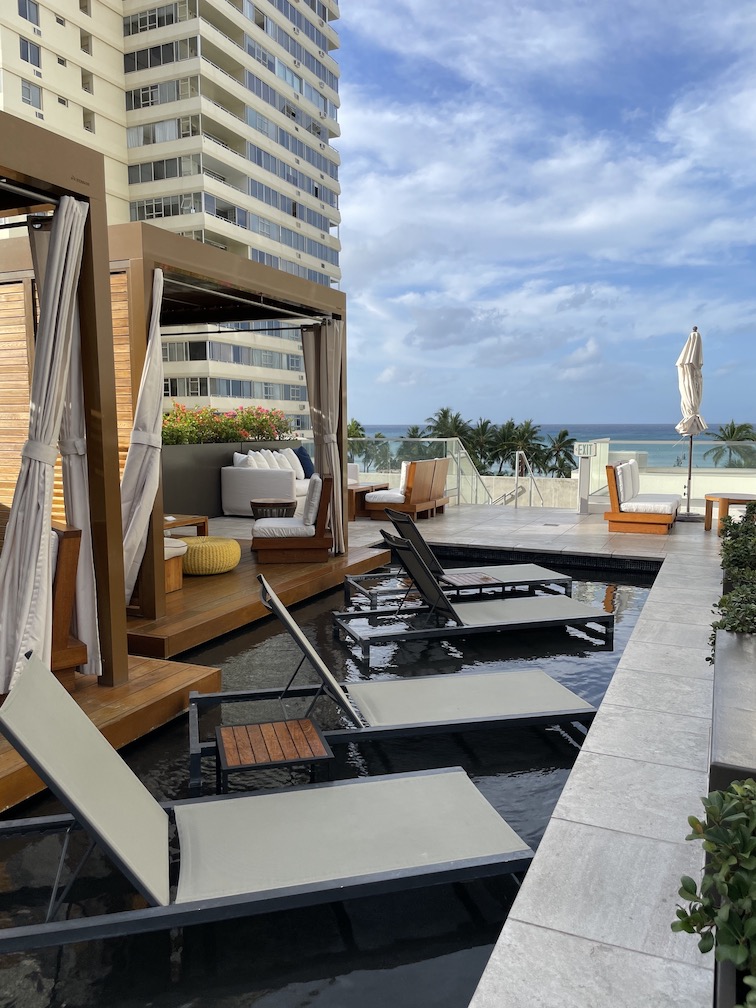 Review & Video: 'Alohilani Resort Waikiki Beach, A Unique Oasis Hawaii Calling a pool with lounge chairs and a building in the background