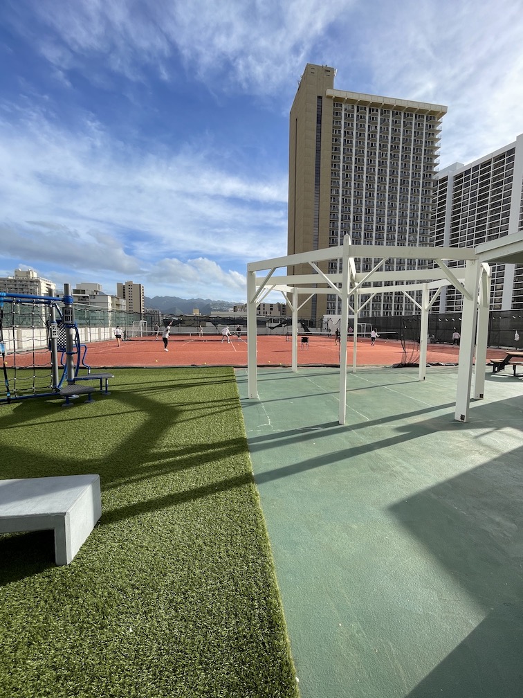 Review & Video: 'Alohilani Resort Waikiki Beach, A Unique Oasis Hawaii Calling a playground with a tennis court and a city in the background