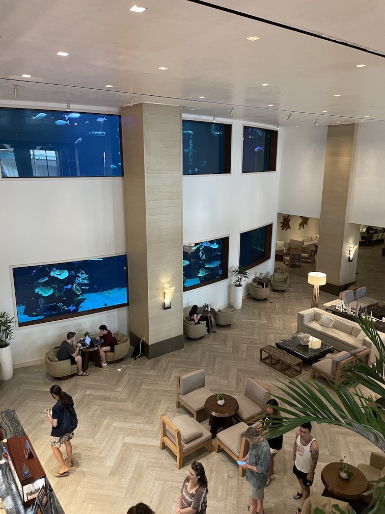 Review & Video: 'Alohilani Resort Waikiki Beach, A Unique Oasis Hawaii Calling a room with fish tanks and people sitting on chairs