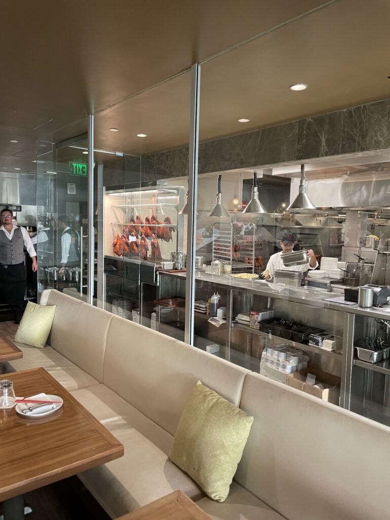 Review & Video: 'Alohilani Resort Waikiki Beach, A Unique Oasis Hawaii Calling a restaurant with a couple of people standing in front of a glass wall