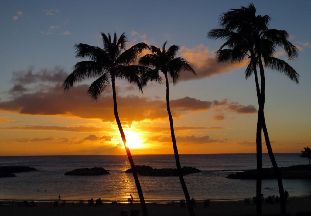 10 Best Sunset Spots On Oahu Hawaii Calling a sunset over a beach with palm trees