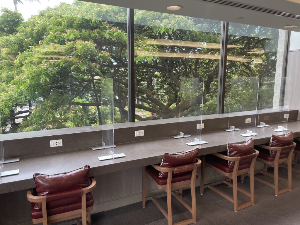 Honolulu Admirals Club | Guide & Review (2025) Hawaii Calling a row of chairs and a row of clear plastic screens