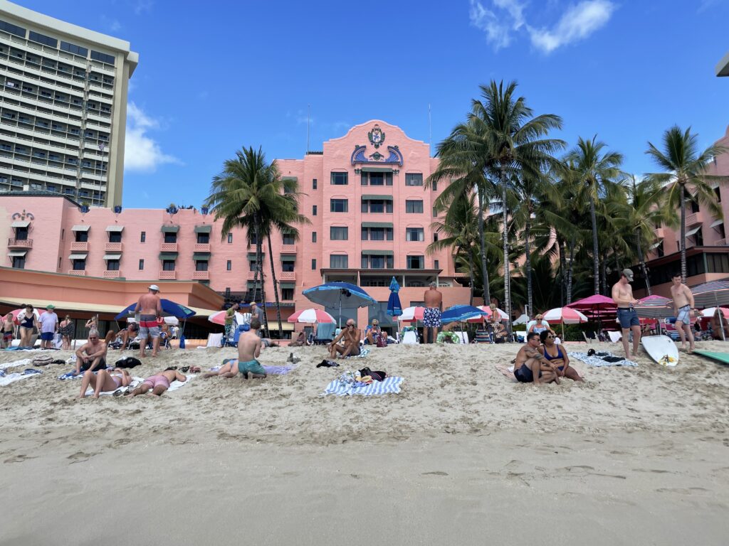 5 Key Features To Know When Deciding Between The Sheraton Waikiki Vs. Royal Hawaiian Hotel Hawaii Calling a group of people on a beach