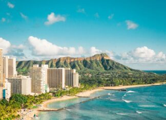 7 Best Luxury Hotels on Oahu (2026) a beach with buildings and a body of water with Diamond Head in the background