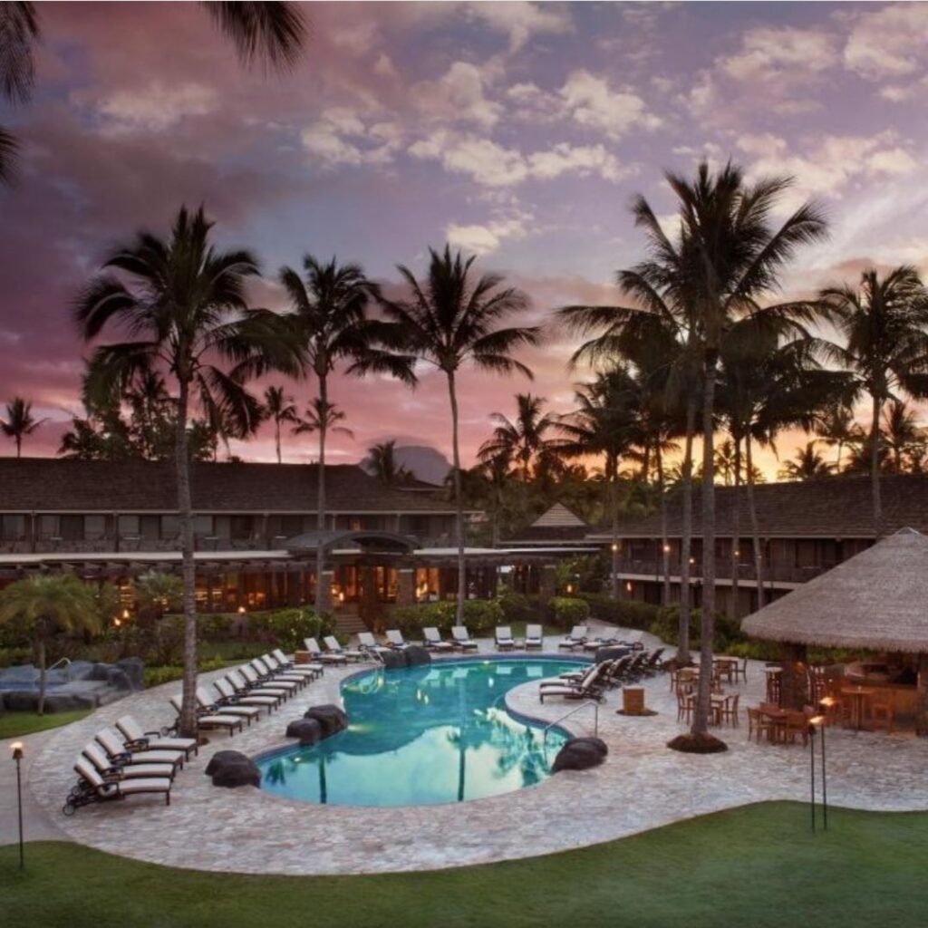 5 Best Luxury Hotels on Kauai (2025) Hawaii Calling a pool with lounge chairs and palm trees in front of a building