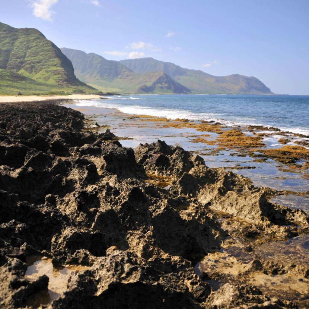 The Perfect Oahu 7 Day Budget Itinerary 2023 Hawaii Calling rocky beach with mountains in the background