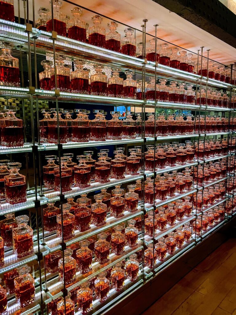 Classy Cool STRIPSTEAK Las Vegas | Review & Video Hawaii Calling a shelf with many glasses filled with red liquid