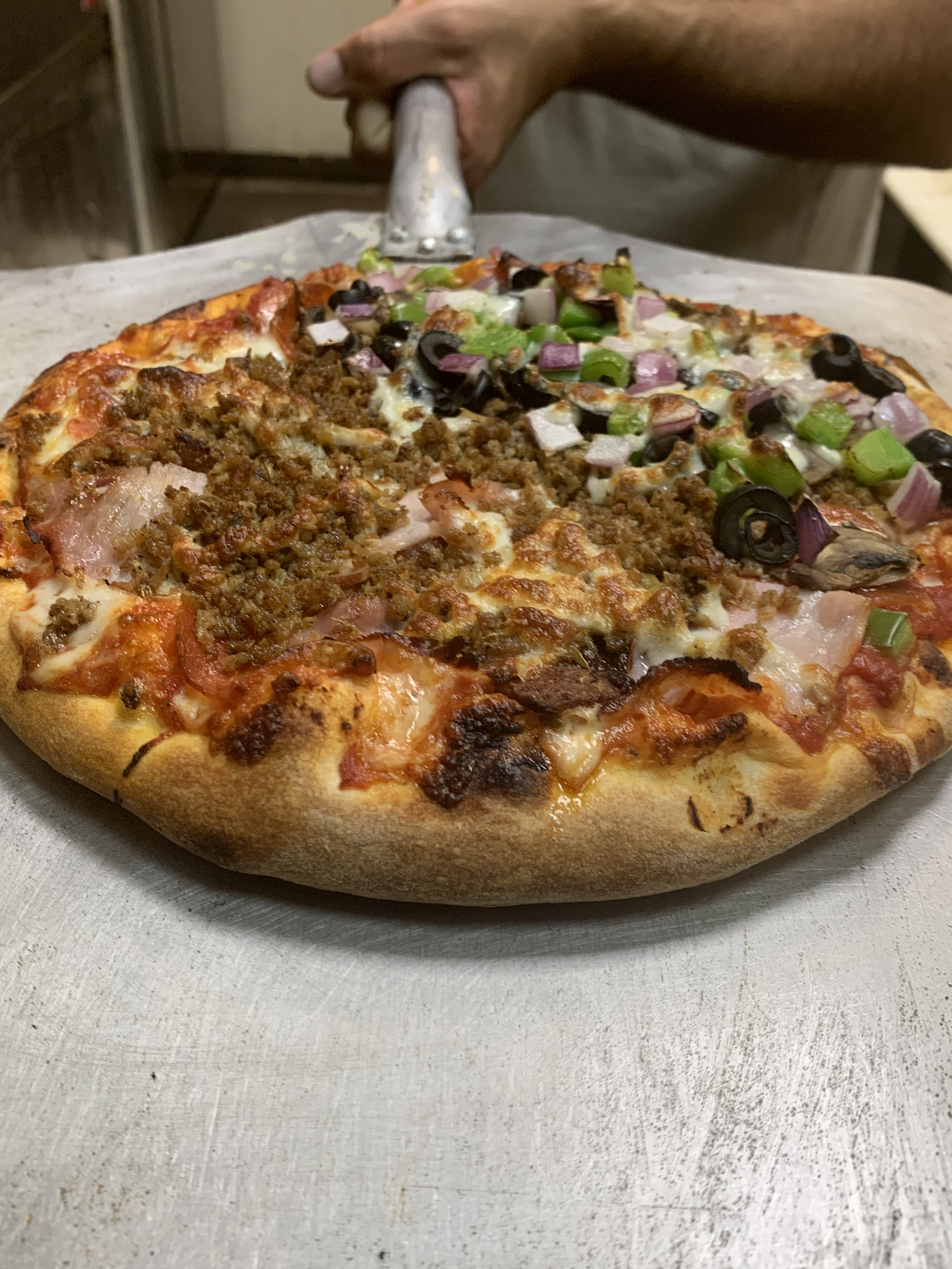 7 Best Pizza Spots In Lahaina, Maui Hawaii Calling a pizza with meat and vegetables on a white surface