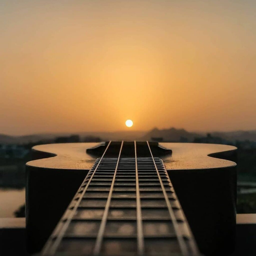 The 10 Best Music Festivals In Hawaii Hawaii Calling a guitar on a balcony with the sun setting in the background