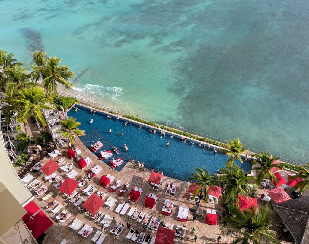 Legendary Sheraton Waikiki Vs. Moana Surfrider | 6 Things to Consider Hawaii Calling a pool with lounge chairs and umbrellas by the water