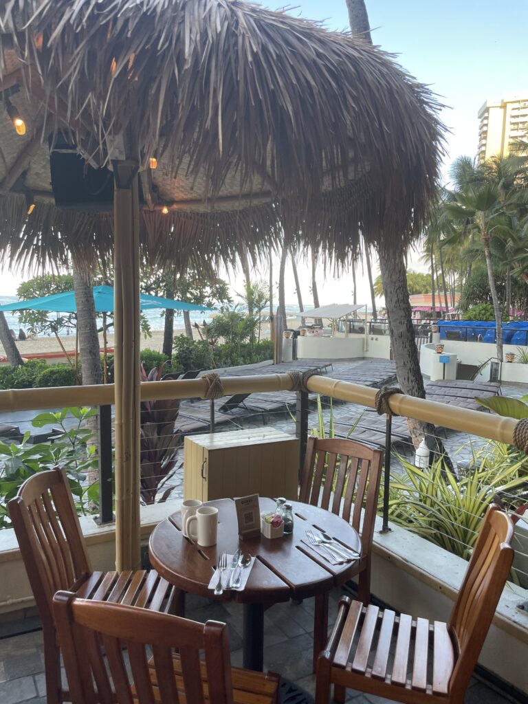 11 Best Sunday Brunch Buffets On Oahu Hawaii Calling a table and chairs on a patio with a straw umbrella
