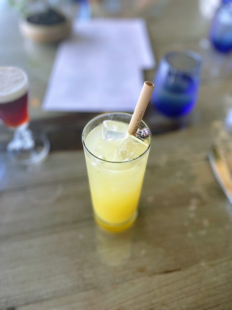 Relaxed Oceanside Hau Tree Brunch Review Hawaii Calling a glass of yellow liquid with a straw in it