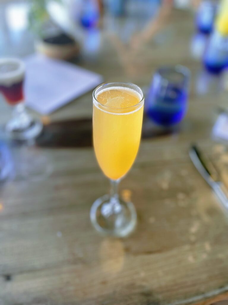 Relaxed Oceanside Hau Tree Brunch Review Hawaii Calling a glass of yellow liquid on a table