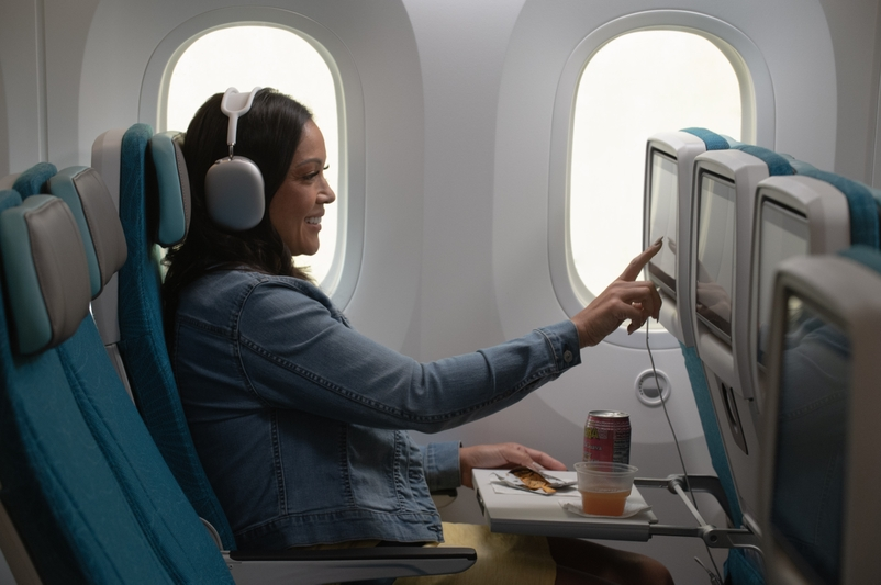 Hawaiian Airlines Reveals Luxurious Boeing 787 Dreamliner Cabins Hawaii Calling a woman sitting in an airplane with headphones on