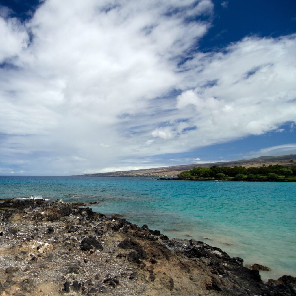 35 Best Things To Do On The Big Island Hawaii Calling a rocky beach with blue water and clouds in the sky