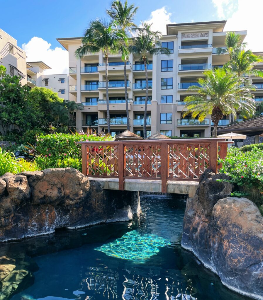 Review Montage Kapalua Bay | Maui Luxury Hawaii Calling a bridge over a pool with palm trees and a building in the background