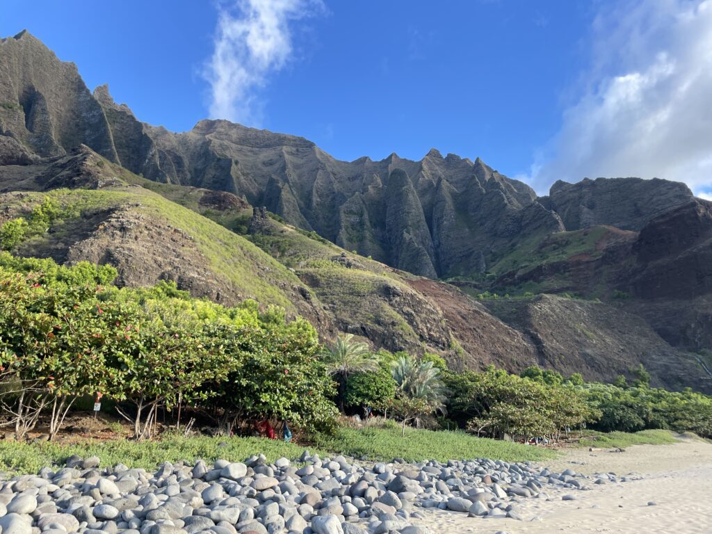 Kalalau Trail Adventure: My Unforgettable Hiking Experience on Kaua'i Hawaii Calling a rocky beach with trees and mountains in the background