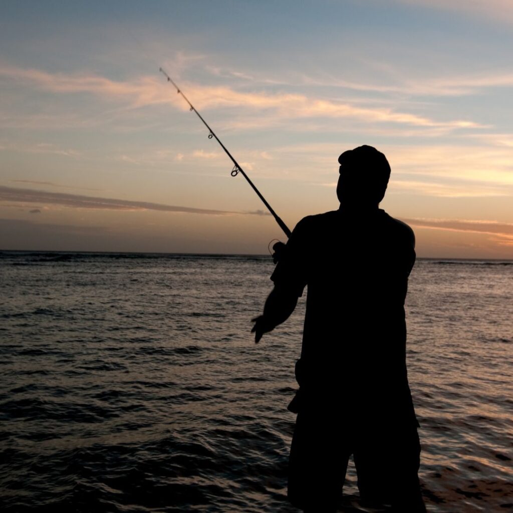10 Breathtaking Honolulu Water Activities You Have To Experience (2025) Hawaii Calling a man standing in the water holding a fishing pole