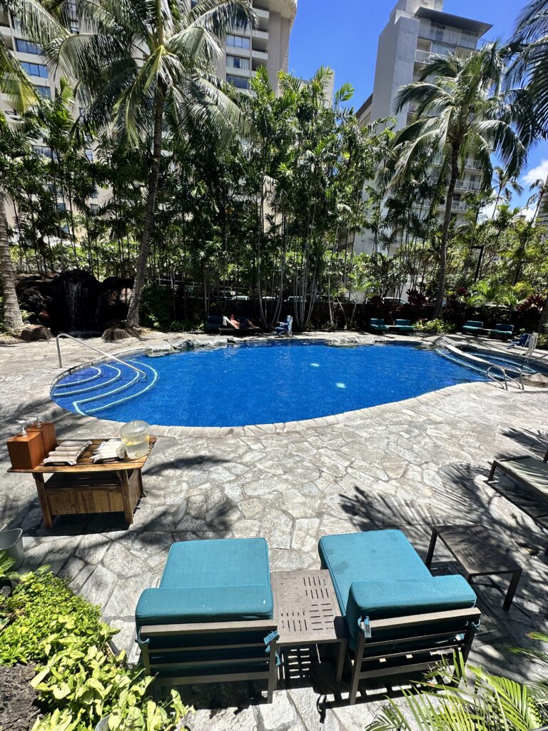 Courtyard by Marriott Waikiki Beach Review | Perfectly Positioned Hawaii Calling a pool with chairs and trees around it