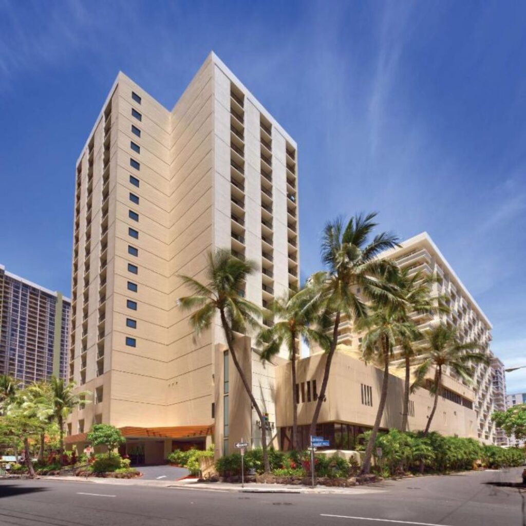20 Best Budget Hotels On Oahu (2025) Comfort and Convenience for Every Wallet Hawaii Calling a tall building with palm trees with Cathedral of Our Lady of the Angels in the background