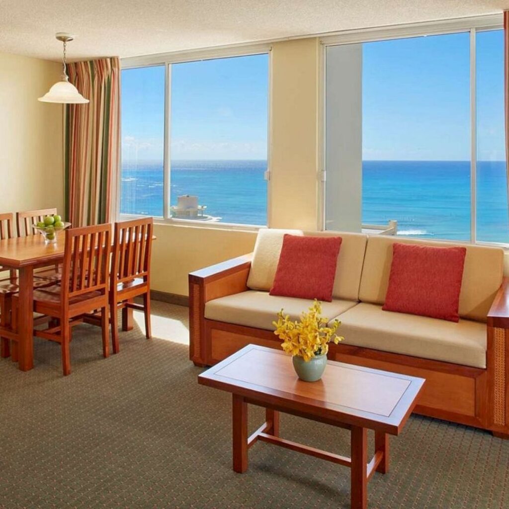 20 Best Budget Hotels On Oahu (2025) Comfort and Convenience for Every Wallet Hawaii Calling a living room with a table and chairs and a couch
