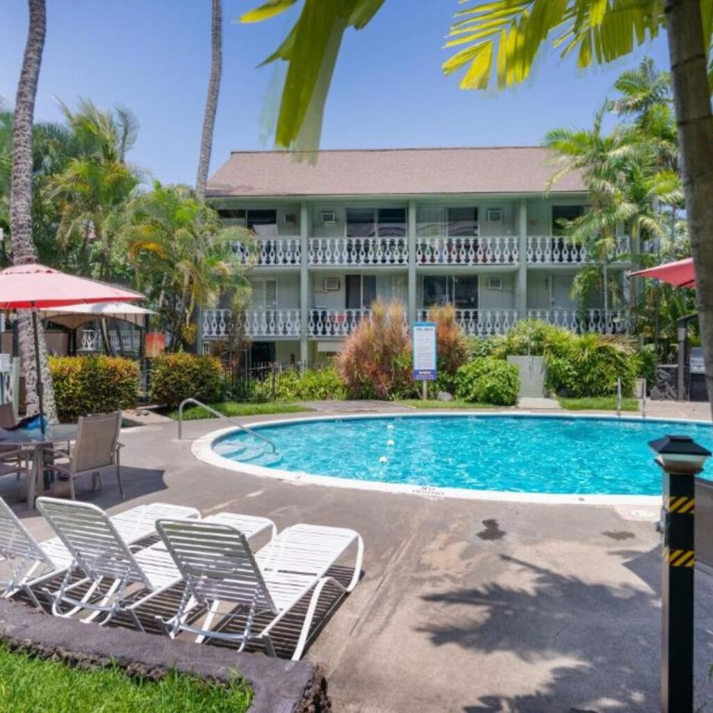 a pool with chairs and umbrellas in front of a building