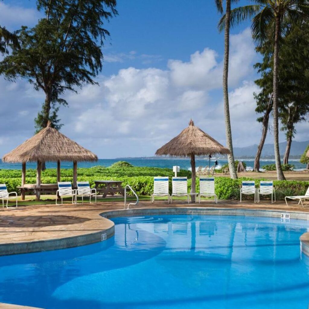 15 Top-Rated Budget Hotels On Kaua'i: Affordable Luxury Hawaii Calling a pool with chairs and umbrellas by the water