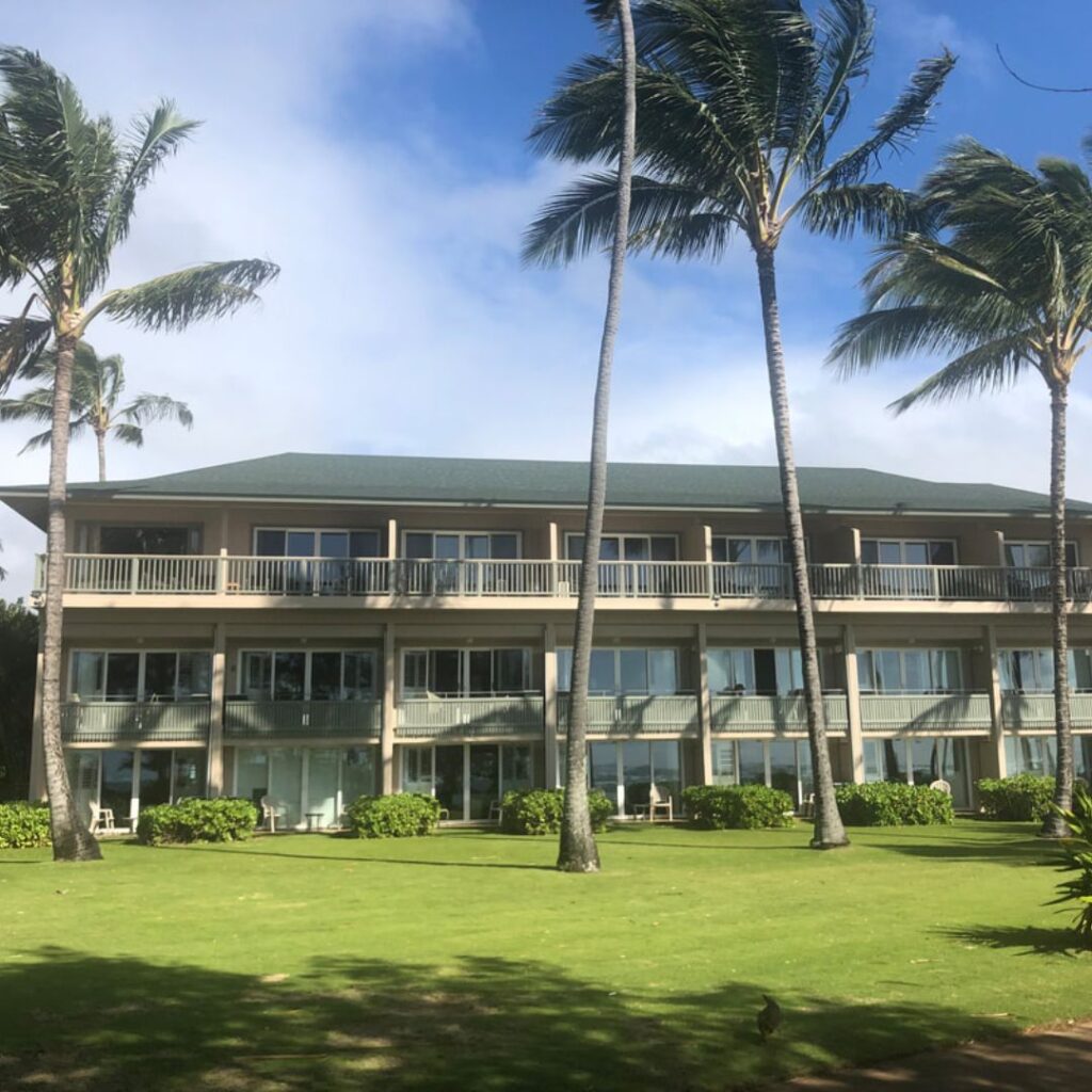 15 Top-Rated Budget Hotels On Kaua'i: Affordable Luxury Hawaii Calling a building with palm trees and grass