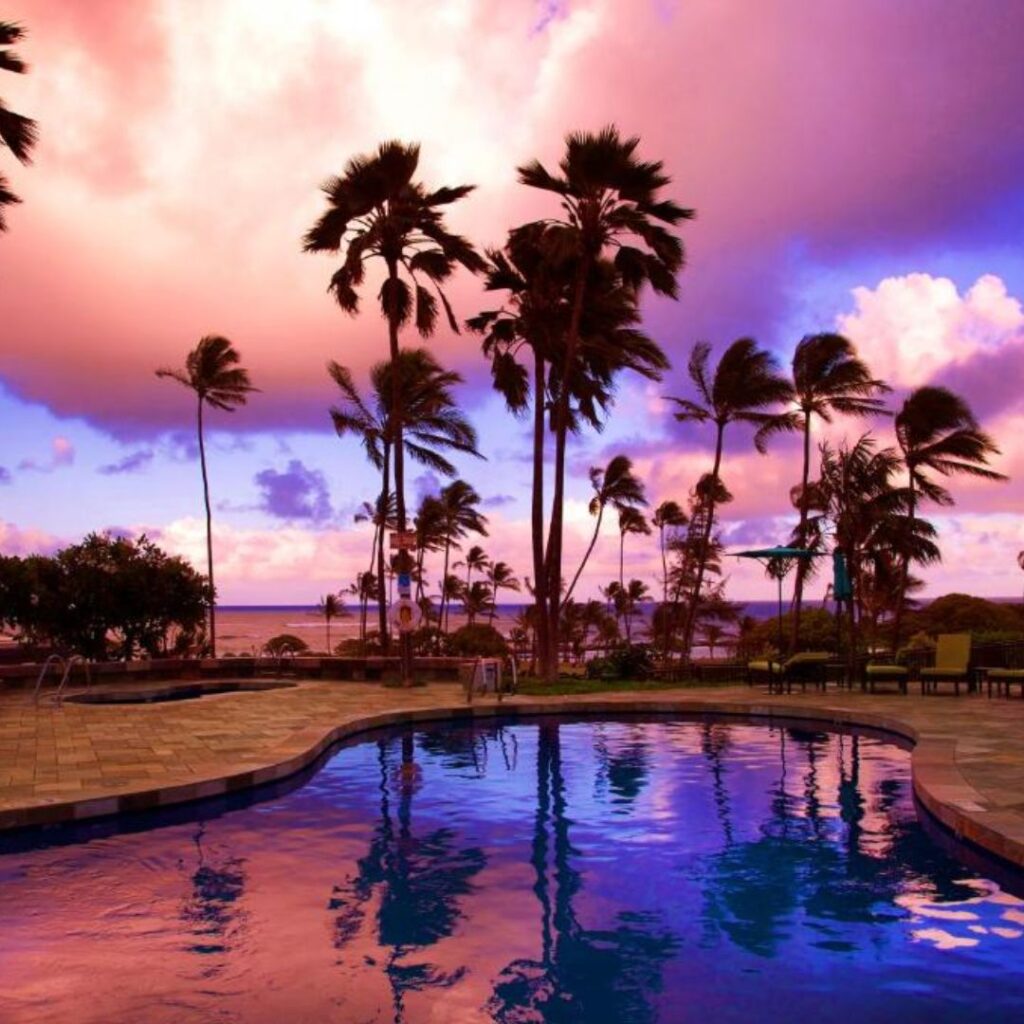 15 Top-Rated Budget Hotels On Kaua'i: Affordable Luxury Hawaii Calling a pool with palm trees and a pink and purple sky