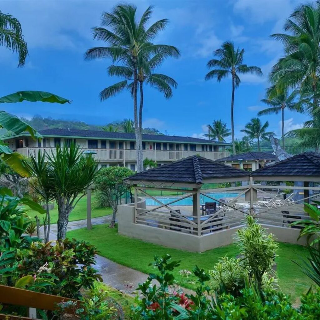 15 Top-Rated Budget Hotels On Kaua'i: Affordable Luxury Hawaii Calling a building with a pool and palm trees