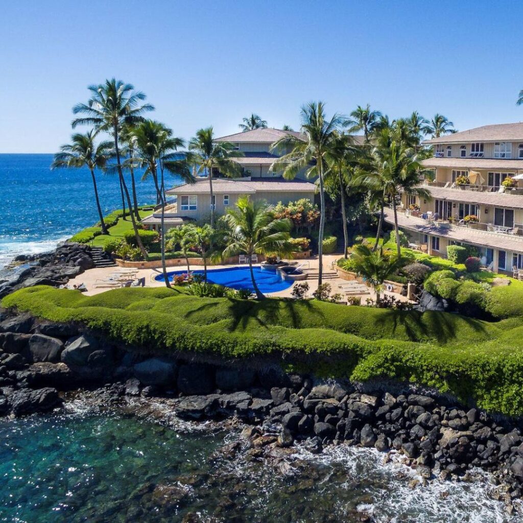 15 Top-Rated Budget Hotels On Kaua'i: Affordable Luxury Hawaii Calling a building with a pool and palm trees on a rocky shore