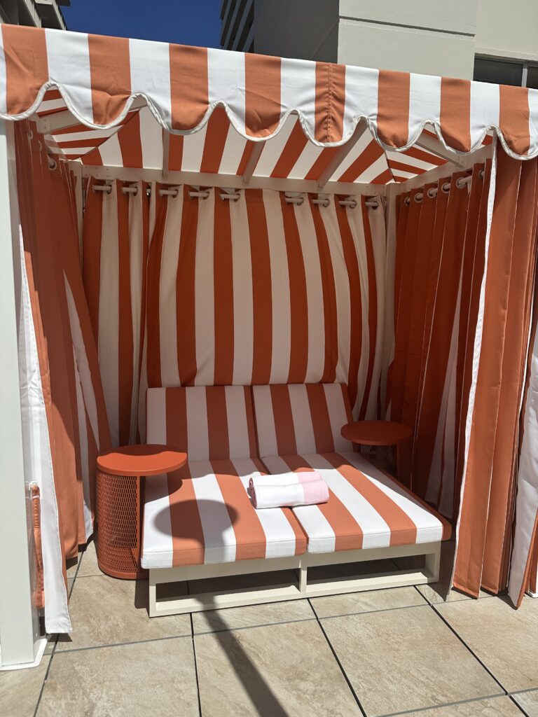 Romer Waikiki Sneak Peek | Renovations Complete Hawaii Calling a striped couch with a table and a towel