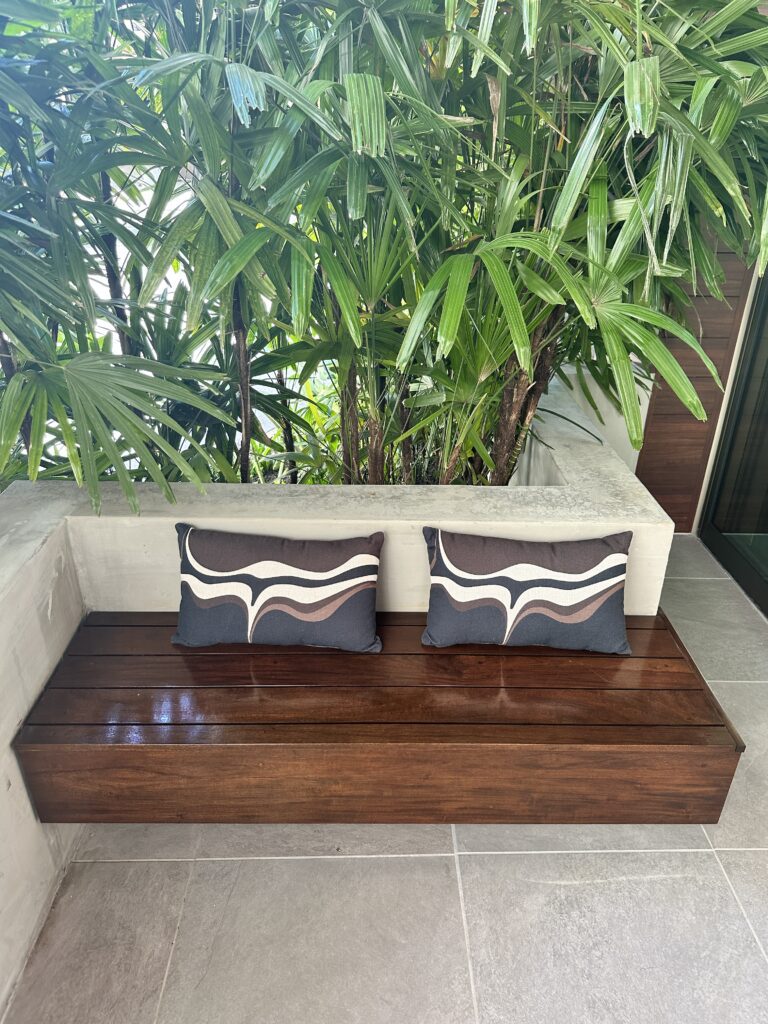Romer Waikiki Sneak Peek | Renovations Complete Hawaii Calling a bench with pillows and a plant behind it