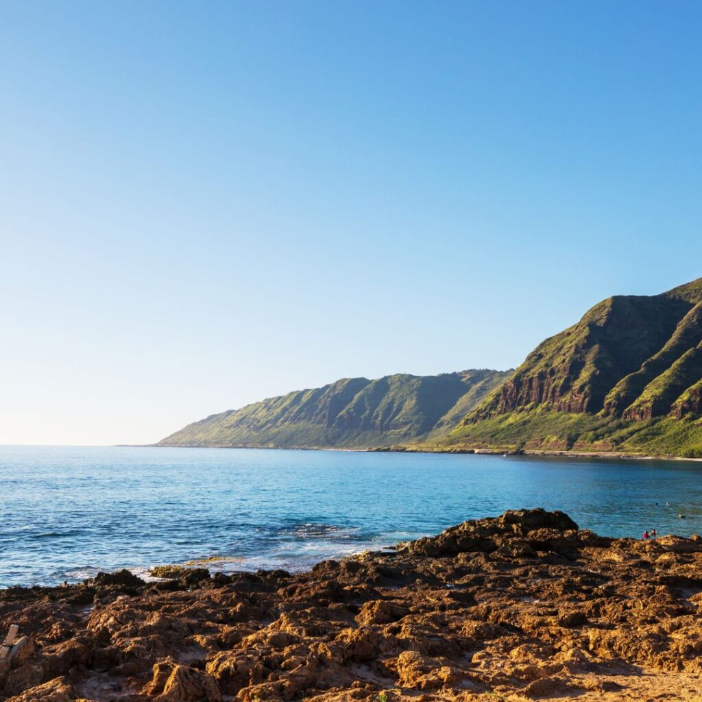 What's the Best Island to Visit in Hawaii in December (2025)? Hawaii Calling a rocky beach with a body of water and mountains