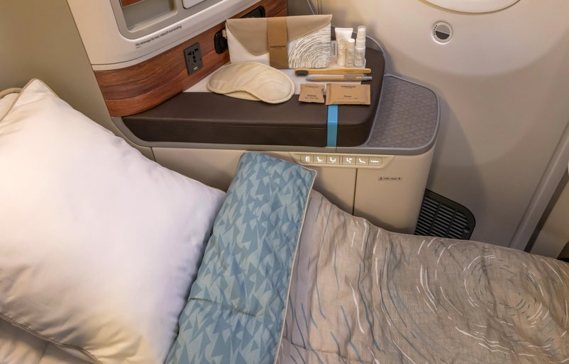 Experience Hawai‘i in the Skies: New Amenity Kits by Noho Home on Hawaiian Airlines Hawaii Calling a bed with a tray and a pillow