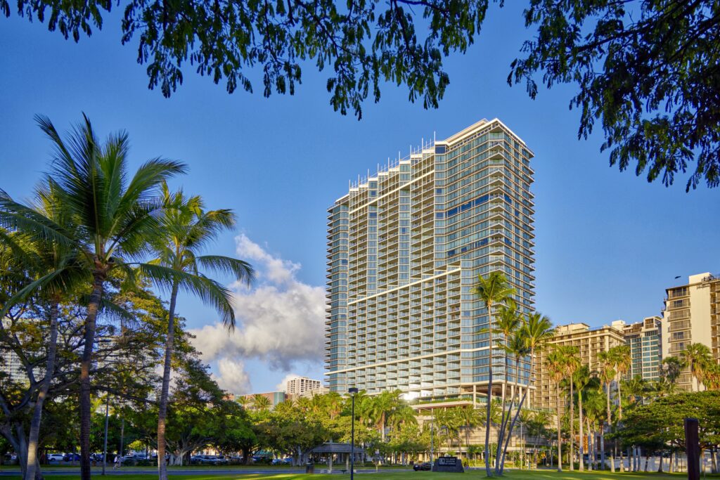 Rebranding Elegance: Unveiling Wākea Waikiki Beach, the Ex-Trump Waikiki Hotel's New Chapter with Hilton LXR Hawaii Calling a tall building with trees and grass