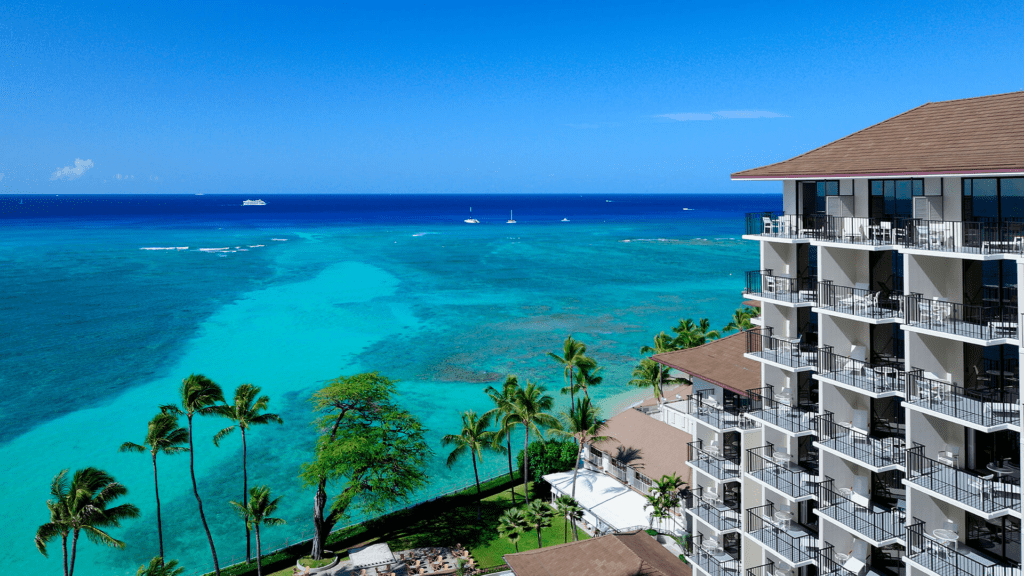 13 Best Luxury Hotels in Hawaii (2025) Hawaii Calling a building with balconies and palm trees next to a body of water