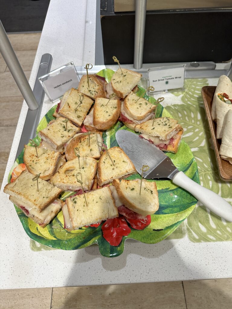 Delta Sky Club Honolulu | Guide & Review (2025) Hawaii Calling a plate of sandwiches with a knife