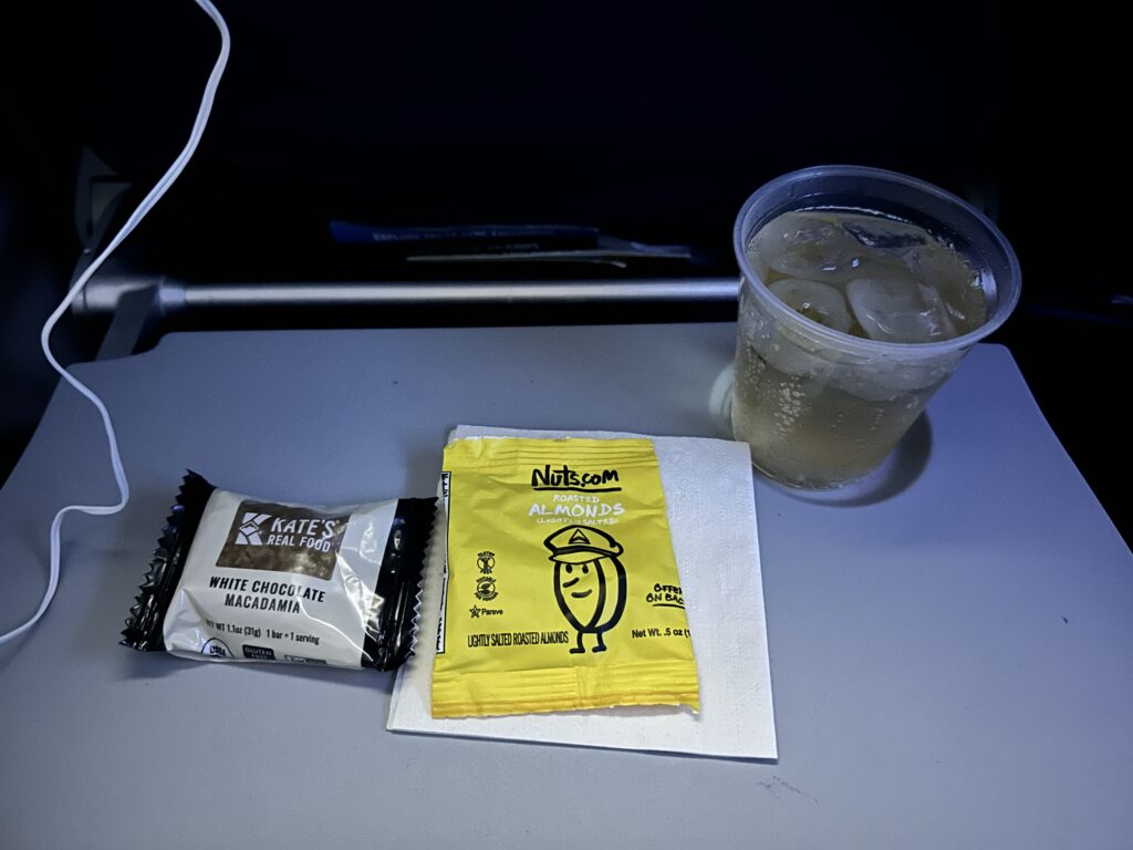 Review: Delta Airlines Economy A321NEO HNL-SEA (Honolulu to Seattle) Hawaii Calling a drink and a packet of sugar on a table